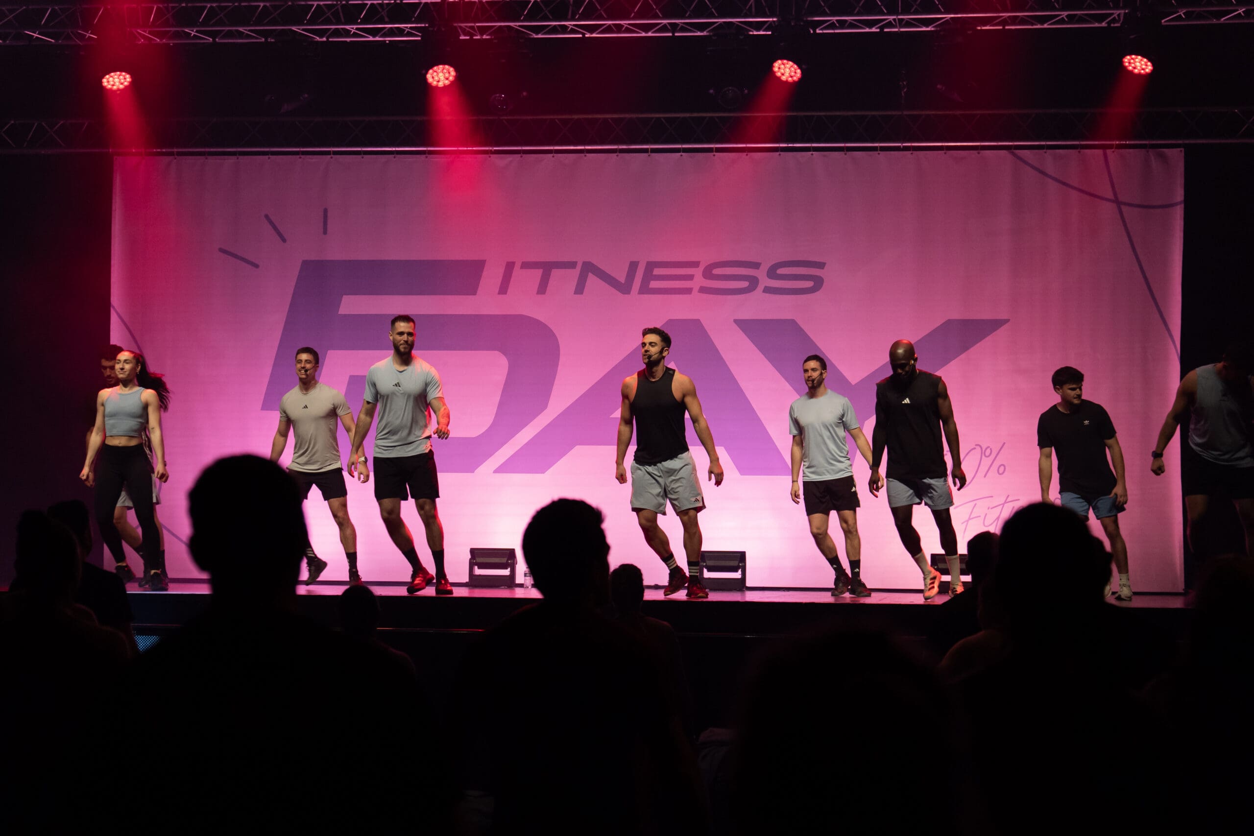 Équipe fitness en action sur scène ambiance rose au FitDay